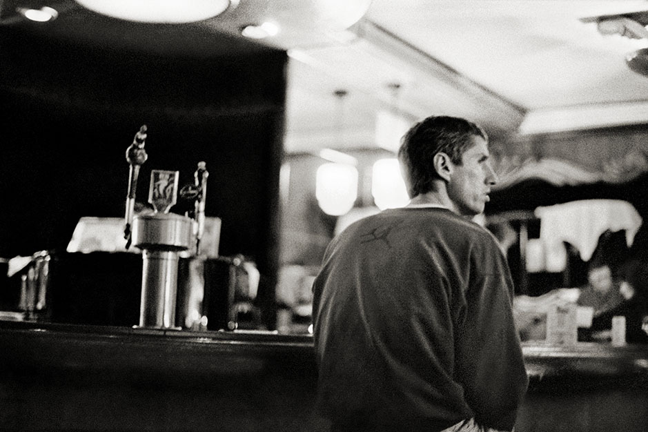 A man, wearing a shirt with an image of Michael Jordan on the back, sits at the bar.