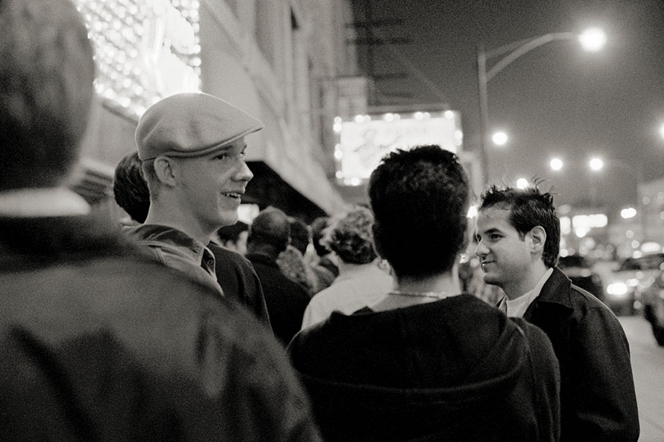 A young man wearing a beret waits outside to get in.