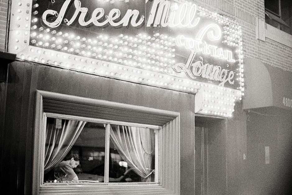 A closeup view of the outside of the building. A man reads in the window.