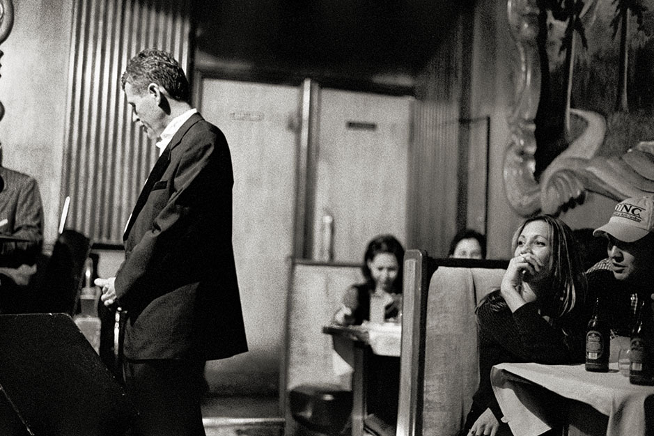 One of the musicians stands to the side of the stage, listening closely.